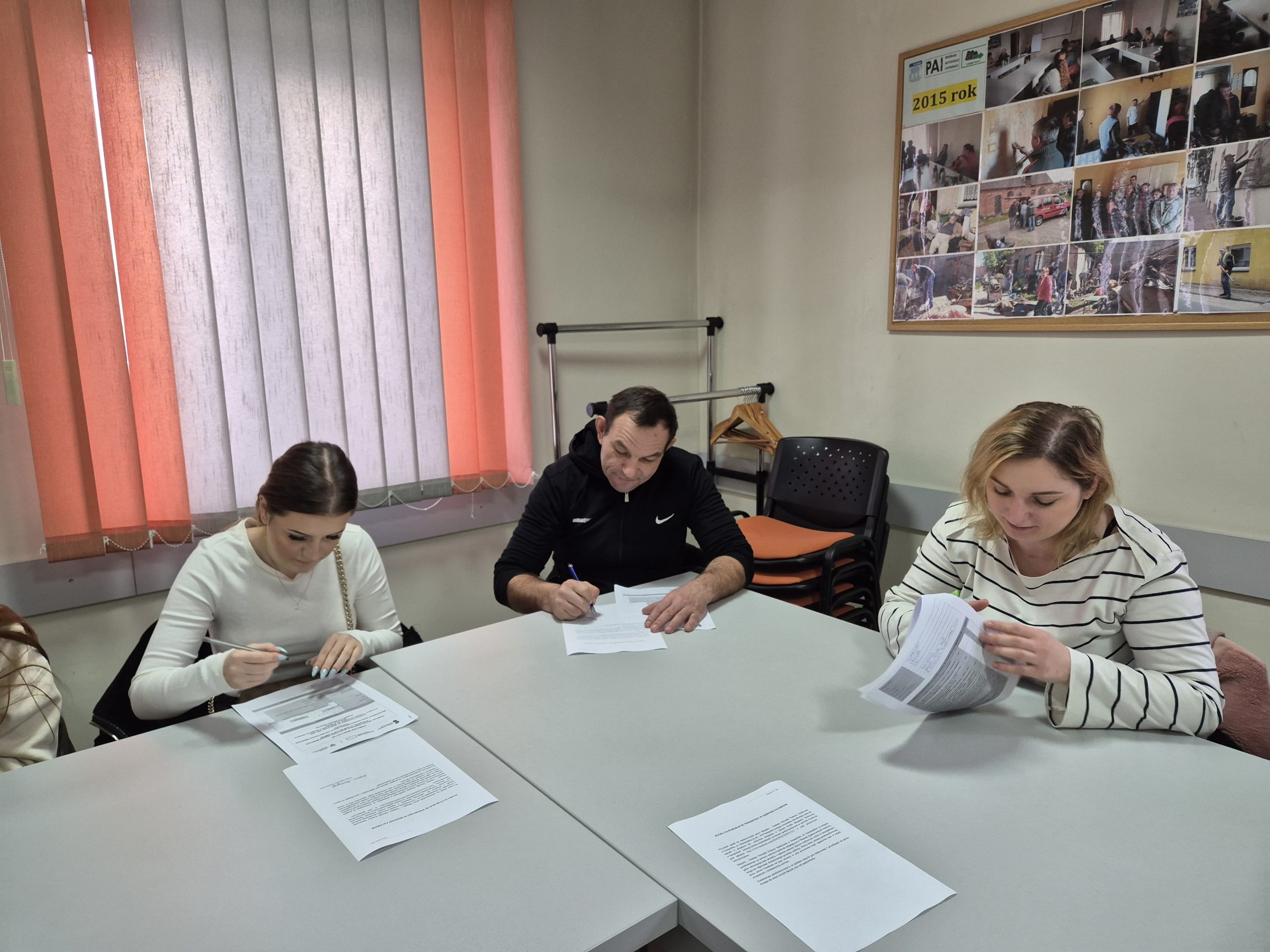 Fotografia przedstawia trzy osoby, które wypełniają dokumenty w ramach udziału w kursie aktywizującym zawodowo