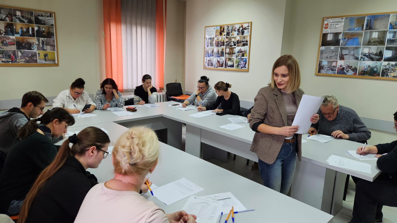 Fotografia przedstawia uczestników szkolenia pracujących nad dokumentami oraz pracownicę M-GOPS w Sompolnie objaśniającą kwestie niejasne dla kursantów