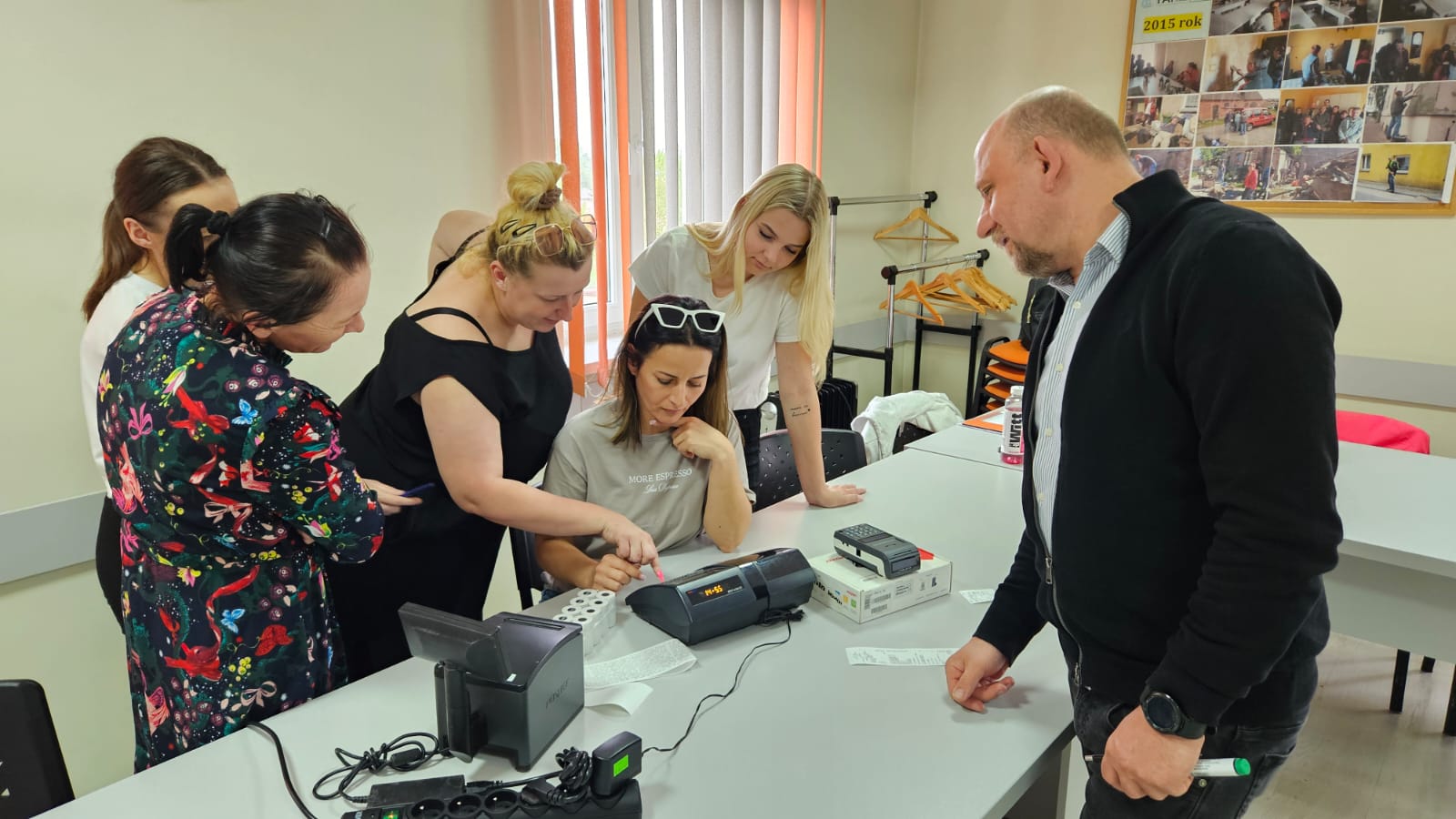 Na zdjęciu widzimy kursantów uczących się obsługi kasy fiskalnej pod okiem instruktora