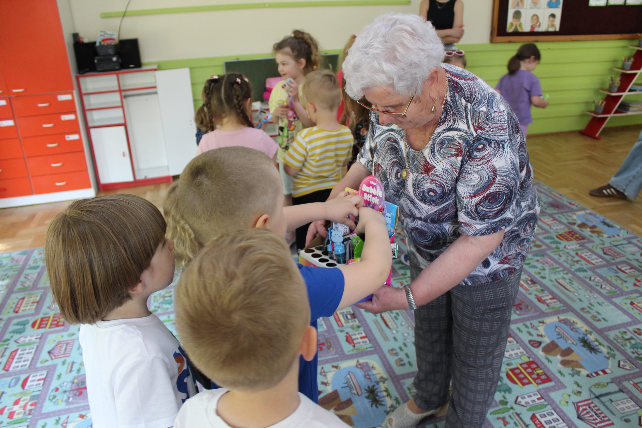 4) Na fotografii seniorka rozdająca dzieciom bańki mydlane.