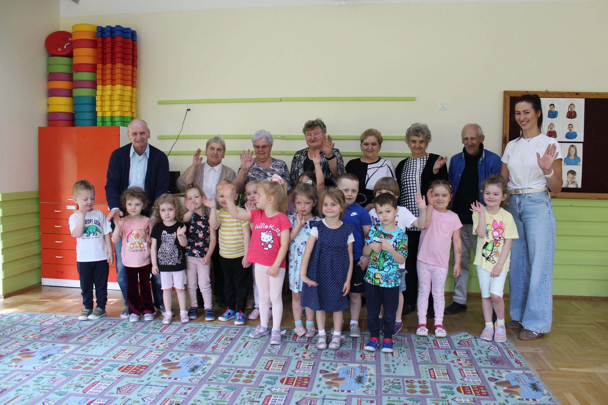 5) Zdjęcie grupowe przedstawia przedszkolaków oraz seniorów podczas odwiedzin z okazji Dnia Dziecka