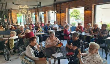 1) Zdjęcie wykonane w restauracji Chwilka w Sompolnie. Przedstawia seniorów z ddp siedzących przy stolikach i jedzących lody.