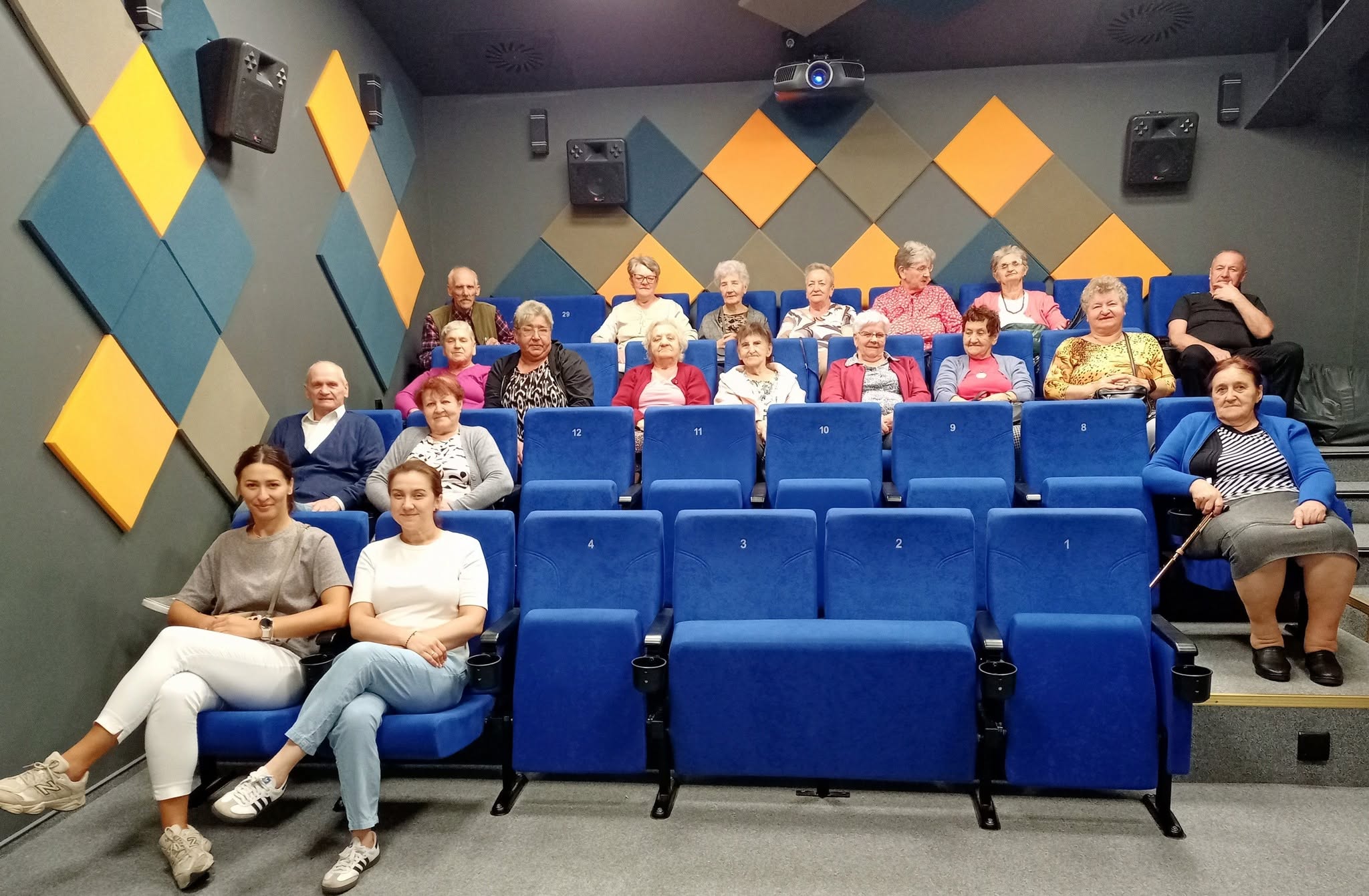1. Zdjęcie wykonane w Kinie za rogiem. Przedstawia całą grupę seniorów w oczekiwaniu na seans filmowy