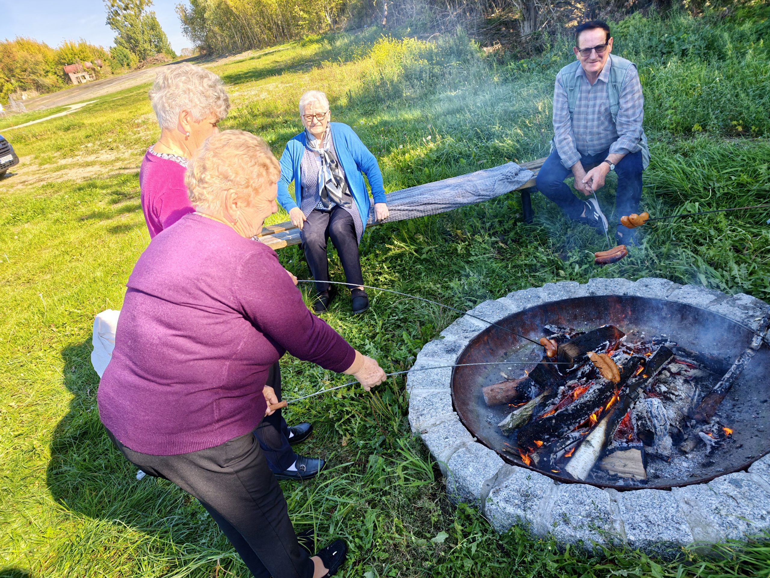 4. Fotografia przedstawia uczestników DDP podczas pieczenie kiełbasek na ognisku