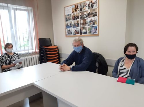 Na zdjęciu znajdują się trzy osoby siedzące przy stole. Wszyscy mają na twarzy maseczki.