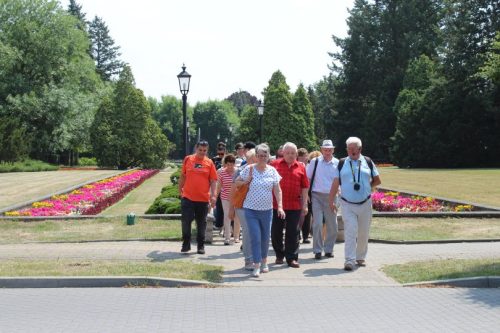 Grupa zwiedzających spaceruje pośród dywanów kwiatowych.