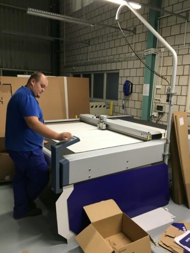 Na zdjęciu znajduje się mężczyzna stojący przy dużym ploterze.